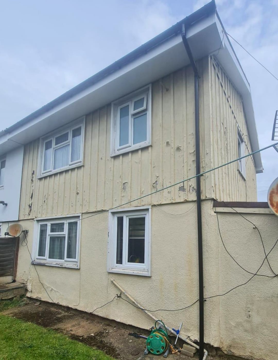 Dated yellow cladding and cracked render in Leamington Spa before facade modernisation.