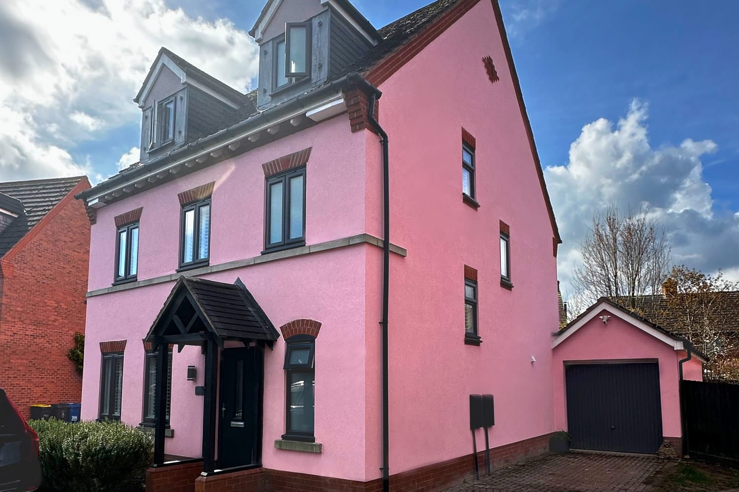 A large detached UK house beautifully finished in a bold, UV-stable pink silicone render by PD Rendering, showcasing the vast colour options available.
